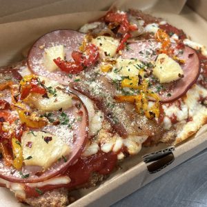 Hawaiian Protein Pizza on our ground chicken crust with ham, marinara, pineapple, bacon, mozzarella and roast bell peppers
