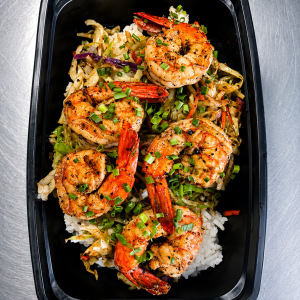 Unwrapped Blackened Shrimp Egg Roll Box with shredded cabbage over white rice